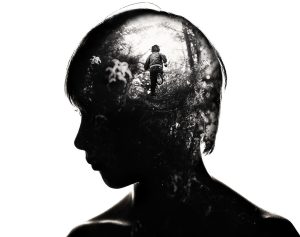 Schattenbild eines Jungen mit einem Blick in sein Gehirn in Bildform. In diesem Bild sieht man einen Jungen in einem Wald laufen, vermutlich vor etwas weglaufen.