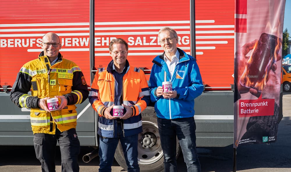 Drei Männer in Warnwesten vor einem Feuerwehrauto